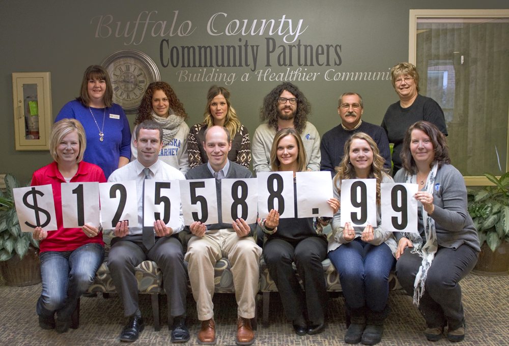 Community Partners’ campaign committee and staff members show off the total amount raised in the 2014 annual fund campaign.